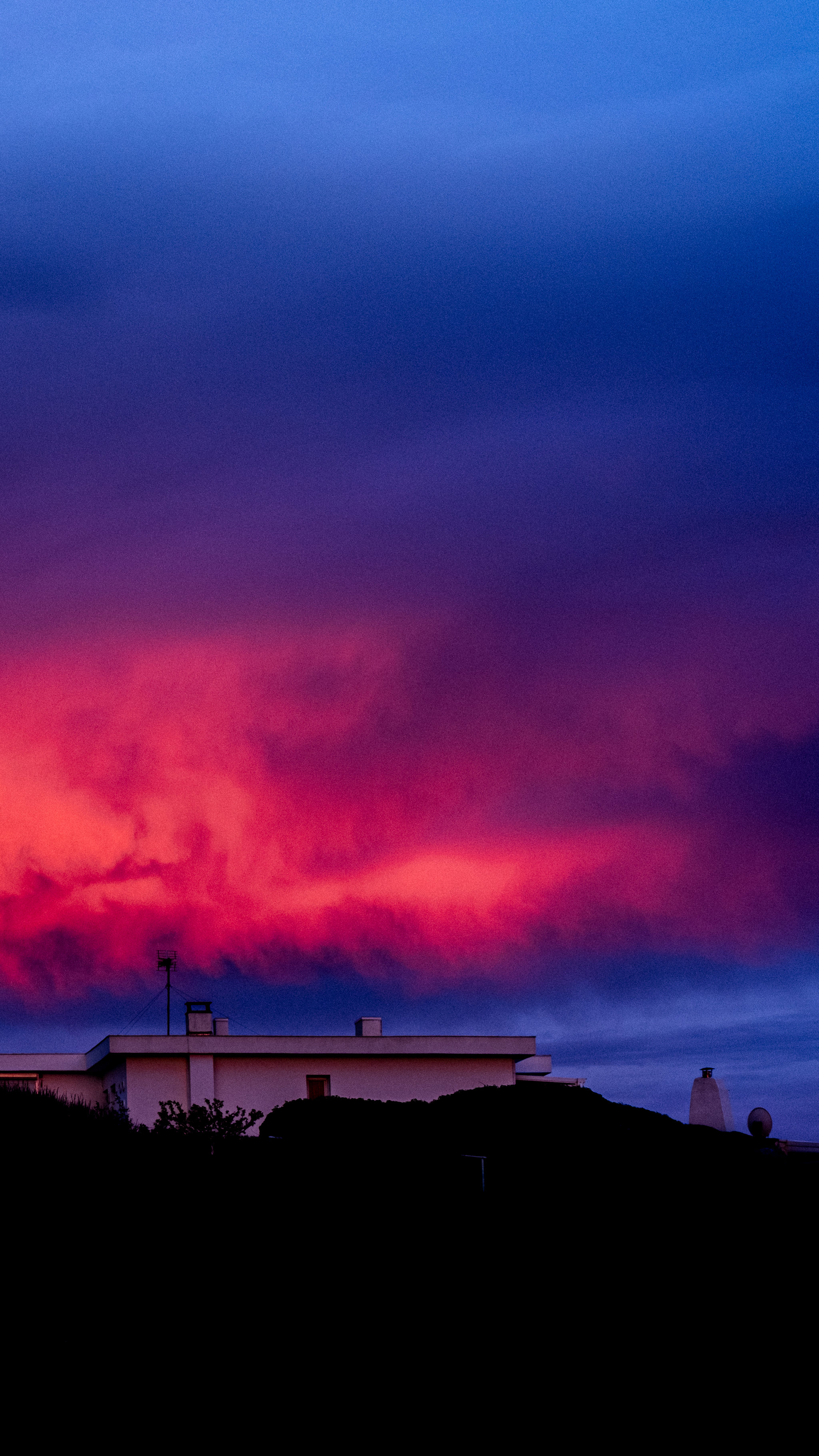 A low building silhouetted beneath blue and magenta storm clouds.