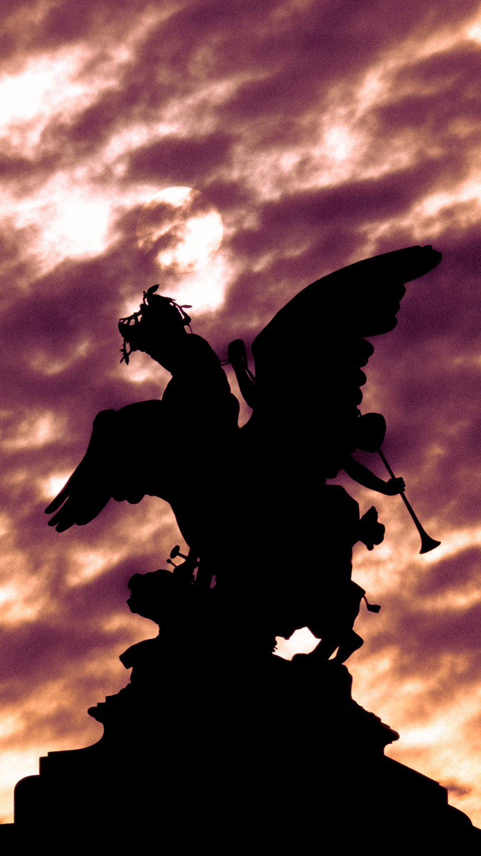 The silhouette of a winged statue against a mottled mauve sky.