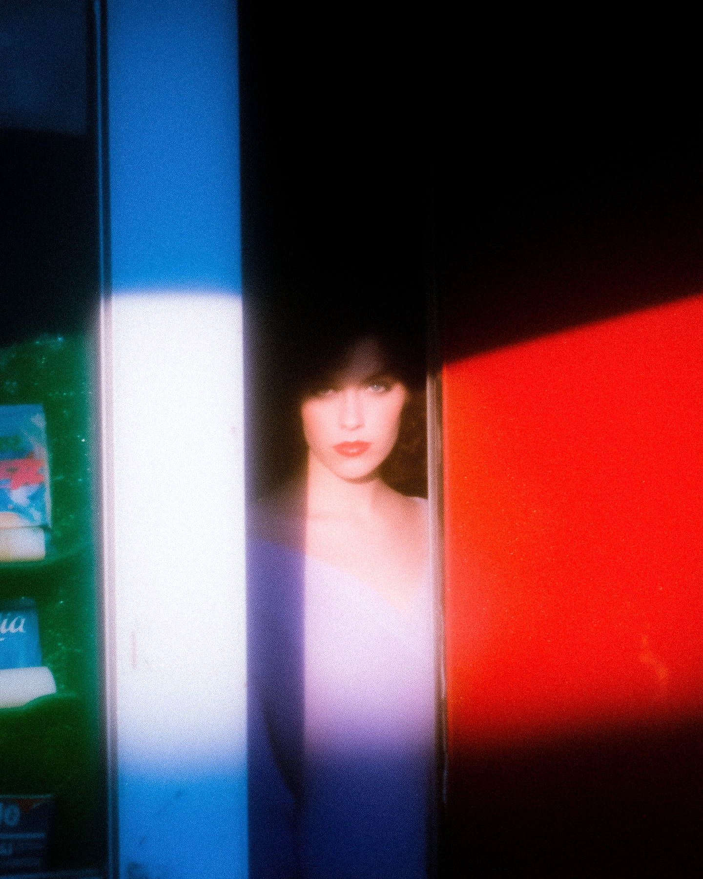 A blurred portrait of a woman between bands of green, blue and red light.